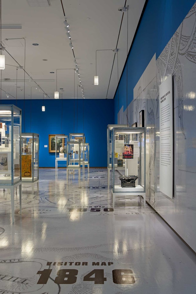 The exhibition design locates vitrines with artifacts on a floor-size map of the cemetery.